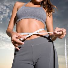 Woman wrapping measure tape around waist.