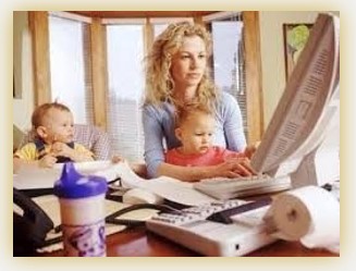 Mom working on computer with two young children at her side